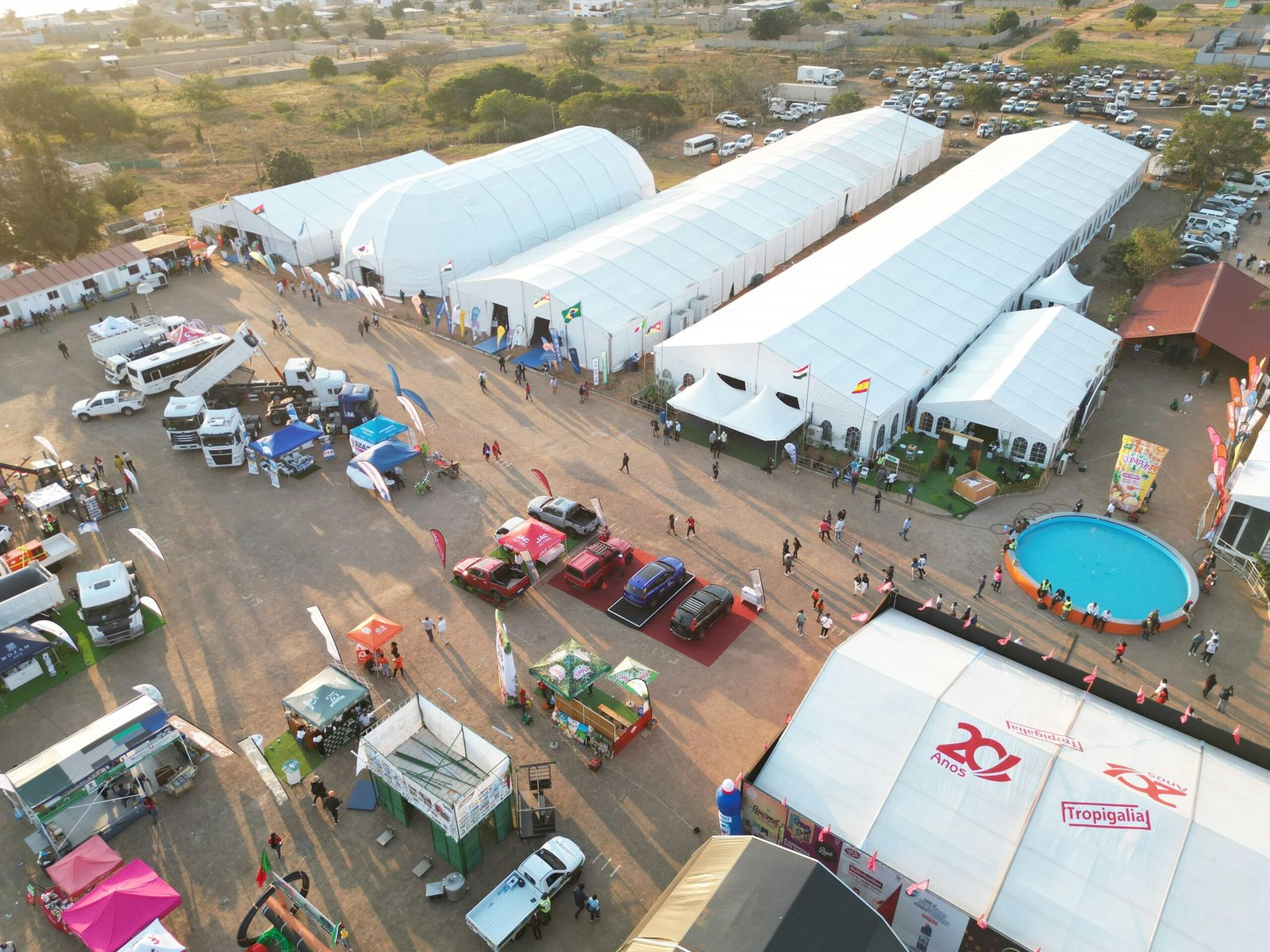 Aerial shot of a lively outdoor event with tents and vehicles in Matola, Mozambique.
